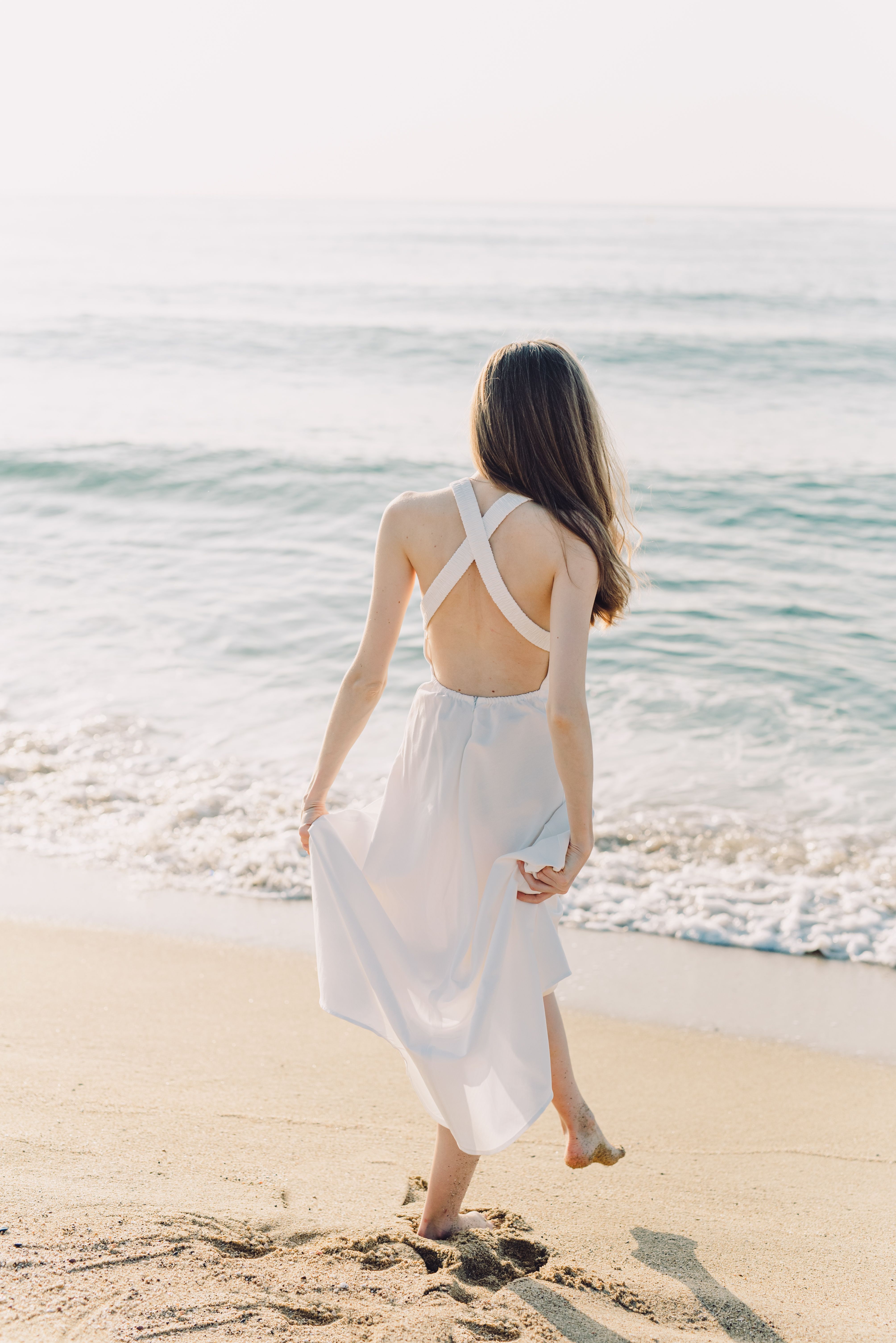 Woman Holding Her Dress While Walking on the Beach · Free Stock Photo