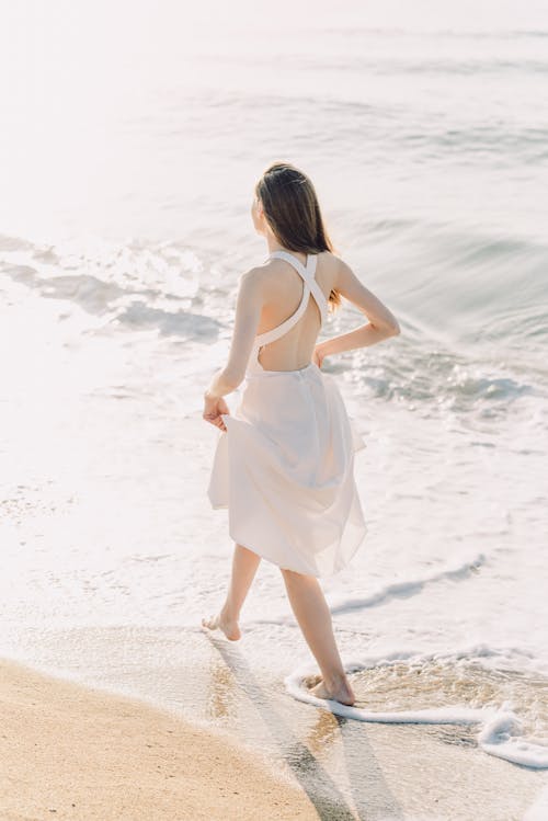 Woman in White Dress Walking on Seashore
