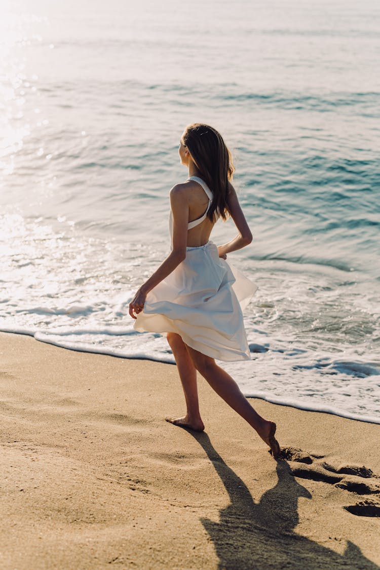 Woman In White Dress Running On The Beach