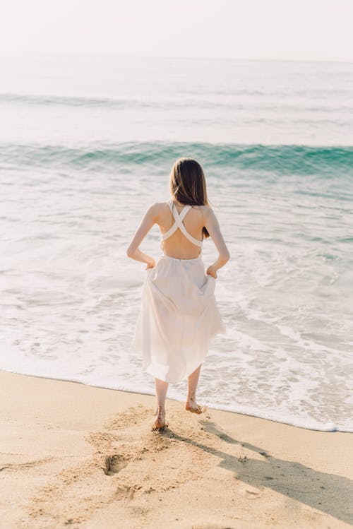 Free Woman Walking on the Seashore Stock Photo