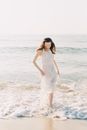 Woman in White Spaghetti Strap Dress Standing on Beach