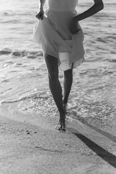 A serene moment captured in black and white, walking by the shoreline in a flowing dress.