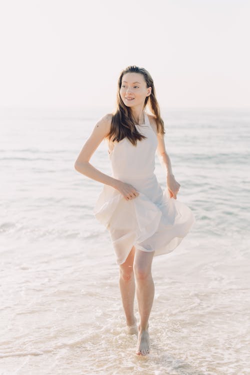 A Woman in White Dress Walking on the Beach 