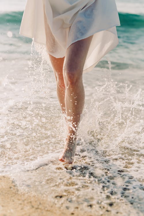 Free Person in White Dress Walking on Beach Stock Photo