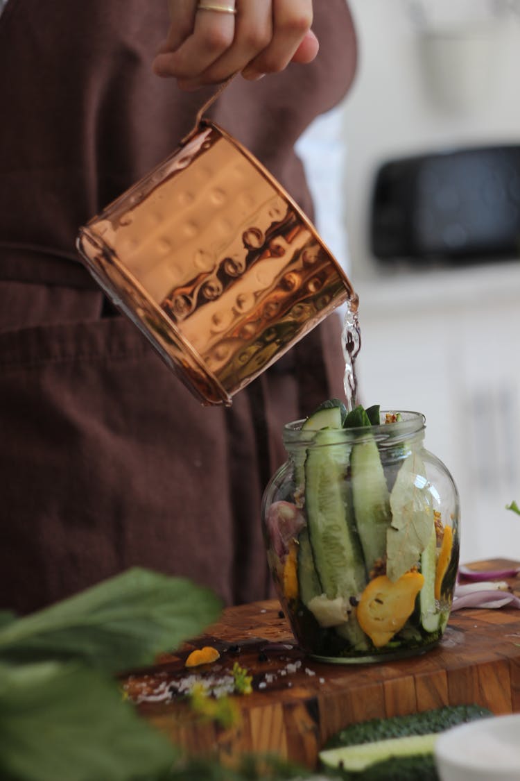 A Person Pouring Water In A Glass Jar