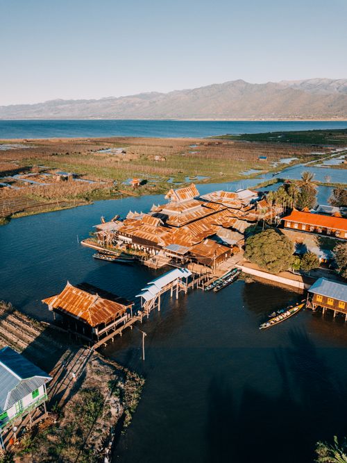 Free Stunning aerial view of traditional wooden houses on Inle Lake, surrounded by serene water and mountain landscapes in Myanmar. Stock Photo