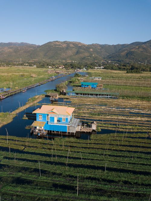 Free Aerial view of floating farm with blue house in Shan, Myanmar, amidst serene landscape. Stock Photo