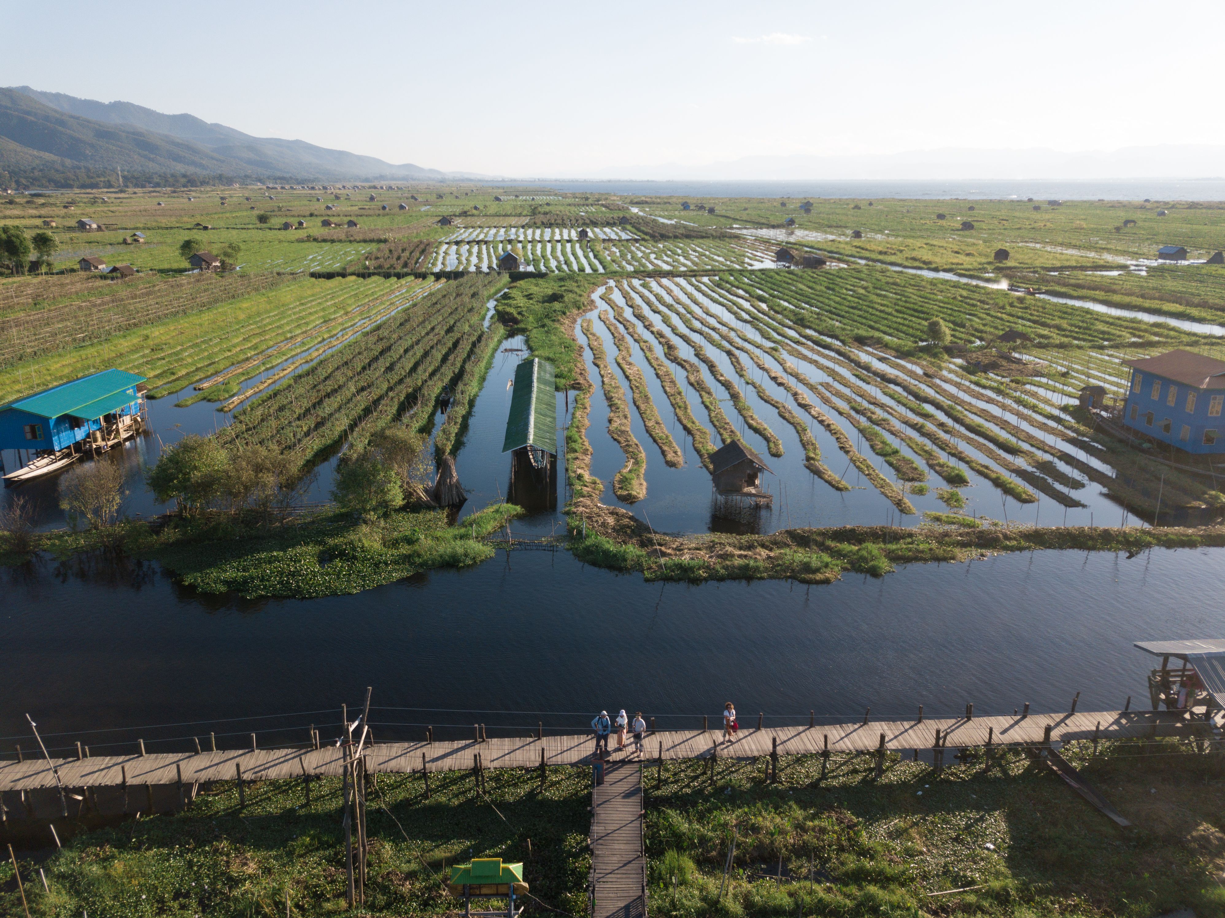 Scenic aerial photo of floating gardens and waterways in Shan State, Myanmar, under a clear blue sky.