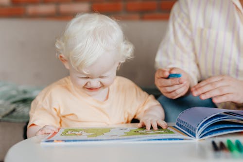 A Child Happily Looking at a Coloring Book