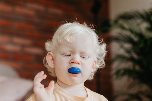 Girl in White Crew Neck Shirt With Blue and Red Pacifier