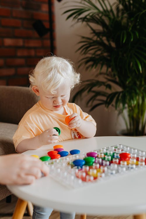 Free Child Playing with Round Colored Objects Stock Photo