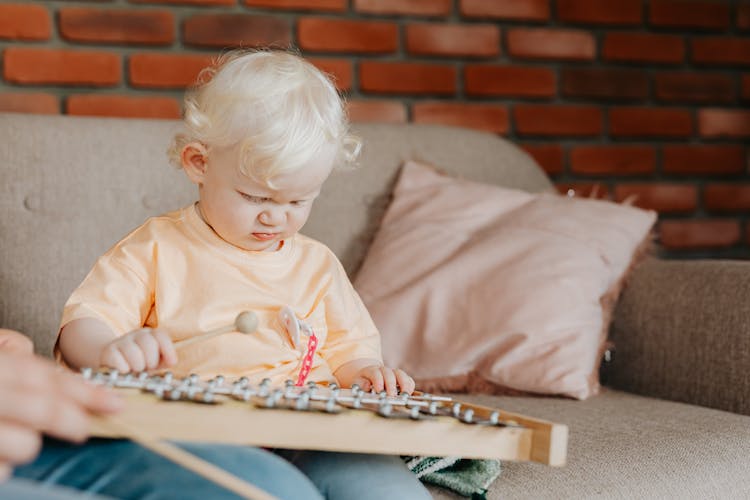 Child In Orange Shirt Playing Xylophone 