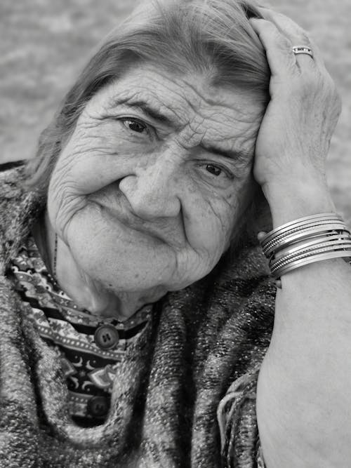 Grayscale Photo of an Elderly Woman with Her Hand on Her Head