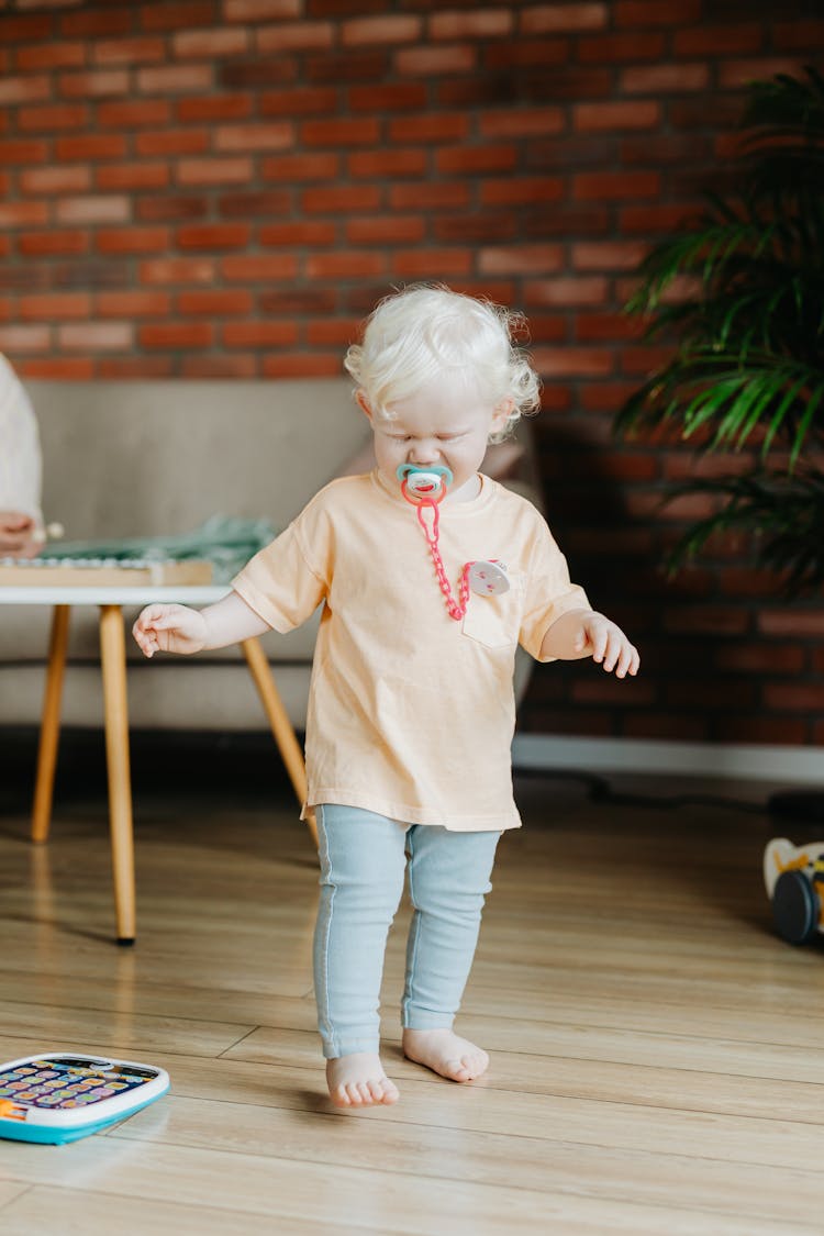 A Toddler Walking With A Pacifier In Her Mouth