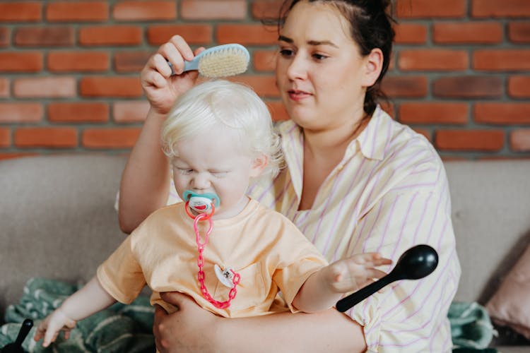 Woman Brushing Baby's Hair