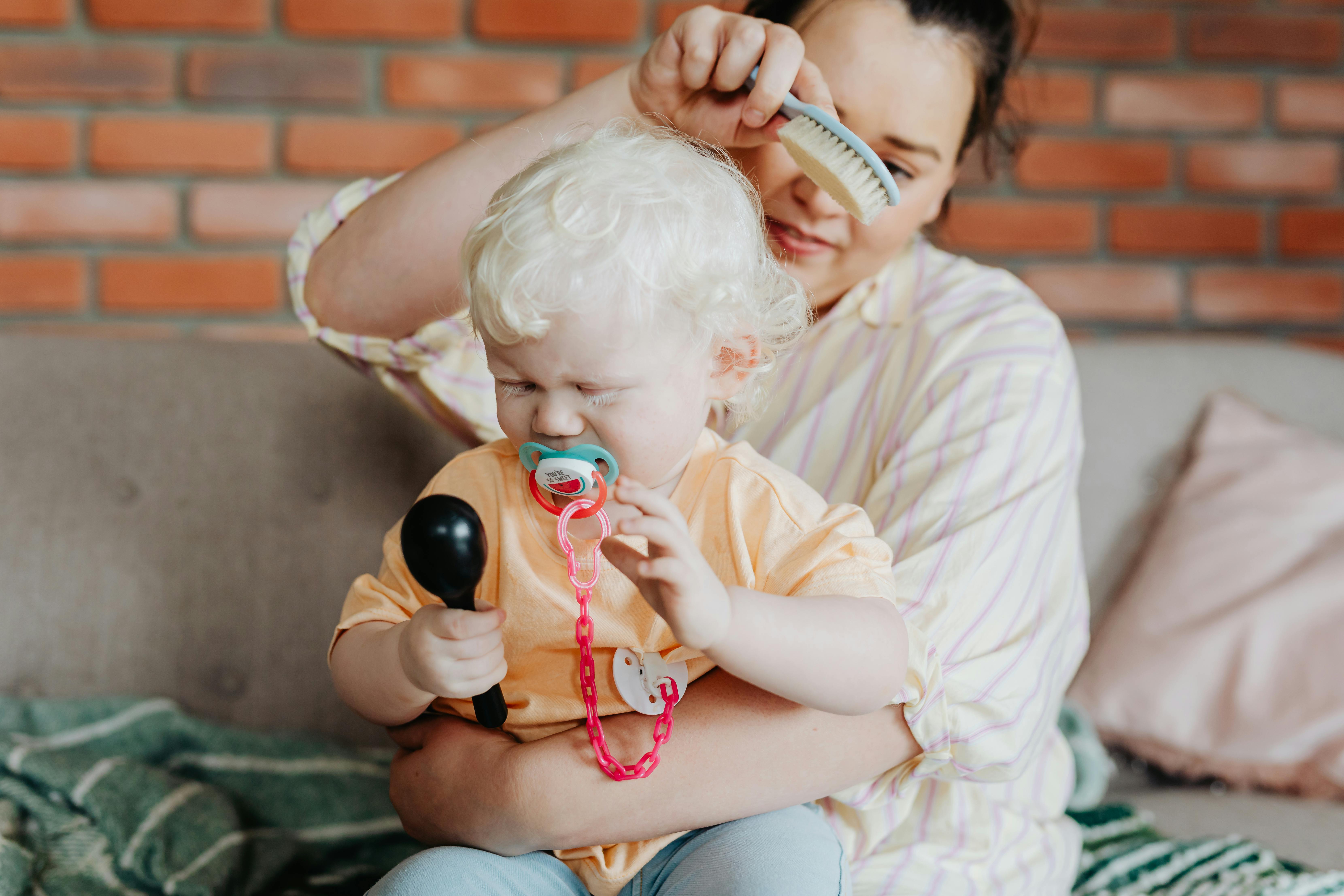 a woman brushing the hair of the crying baby