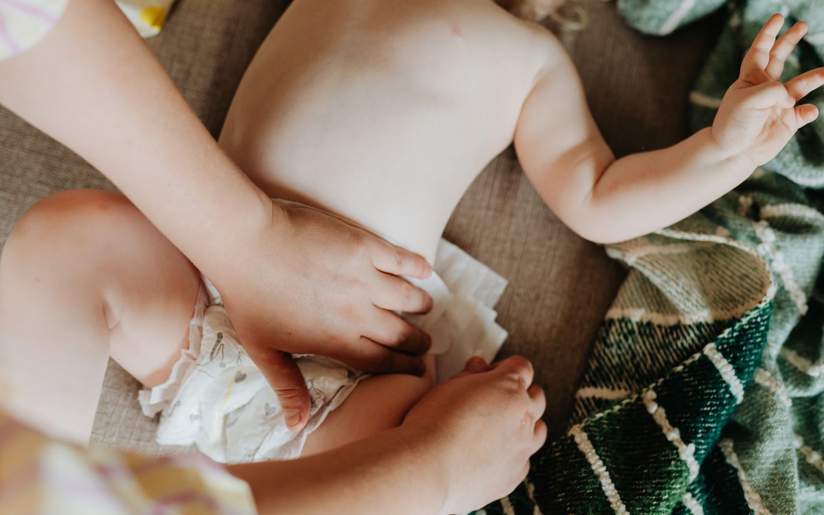 A parent changing a baby's diaper indoors, showcasing nurturing care and parenting.