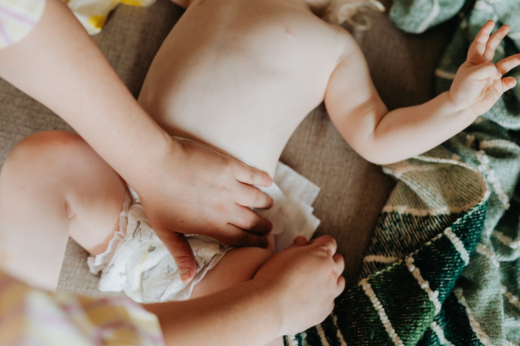 Parent gently putting a fresh diaper on a baby during everyday care