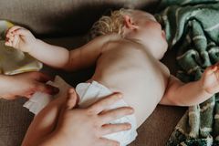 A nurturing moment of a mother changing her baby's diaper on a cozy couch indoors.