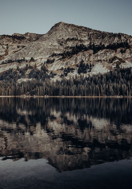 Free Calm lake reflecting rugged mountains under a clear sky in Yosemite National Park. Stock Photo