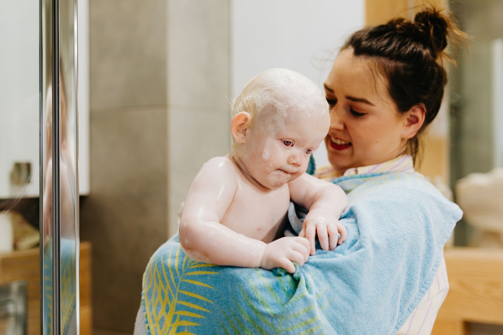 Mother holding a baby wrapped in a soft towel after bath time