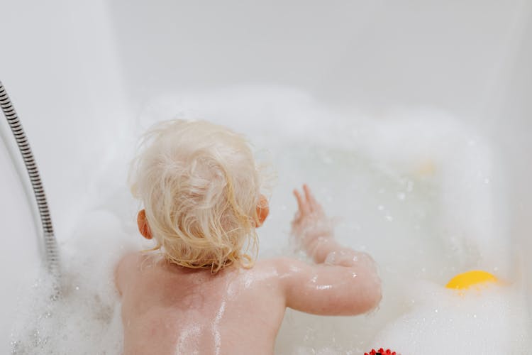 A Kid Enjoying The Soap Bubbles While Bathing