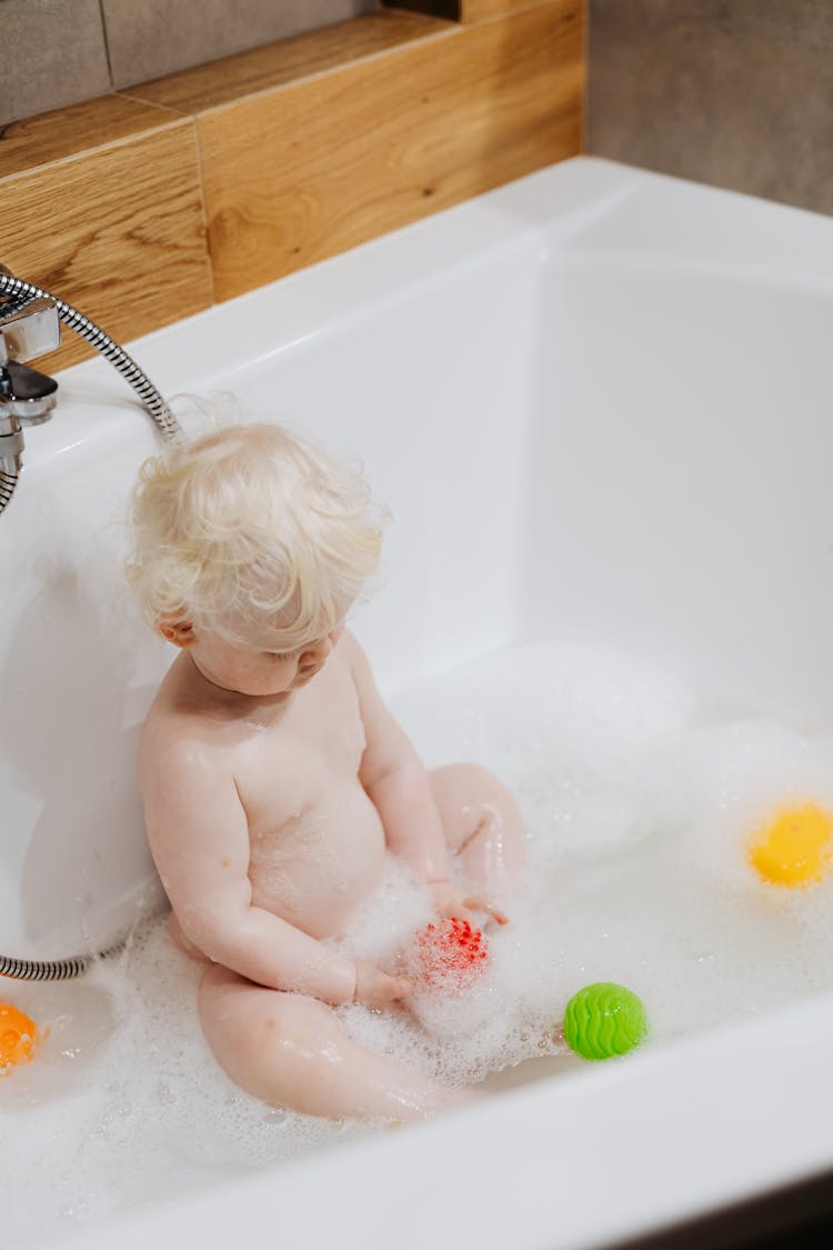 A Toddler Bathing In A Bath Tub