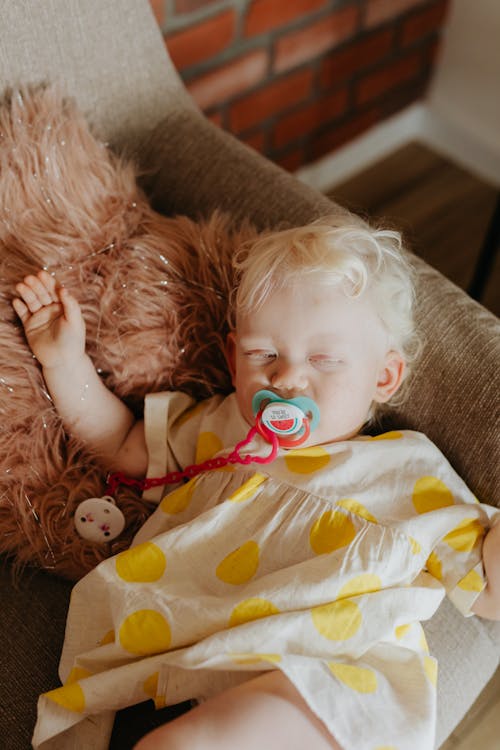 Toddler Sleeping on Brown Sofa with Pacifier