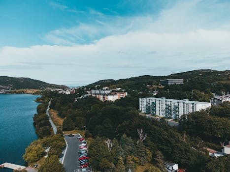 Scenic aerial view of a coastal urban landscape with trees, apartments, and waterway in daytime.