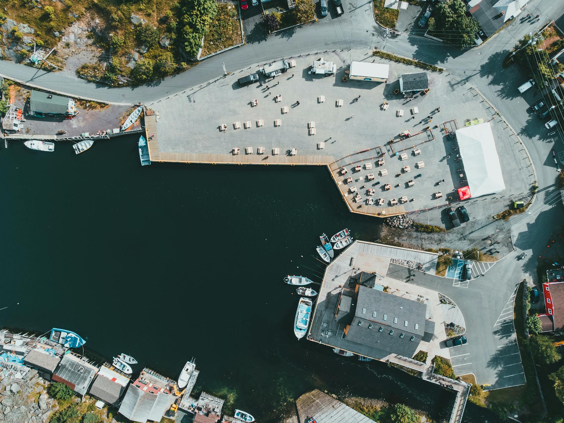 High-angle aerial shot of a coastal marina dockyard with boats and urban infrastructure.