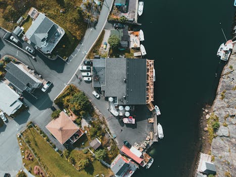 Aerial view of a picturesque coastal neighborhood with houses and marina, showcasing a harmonious blend of architecture and nature.