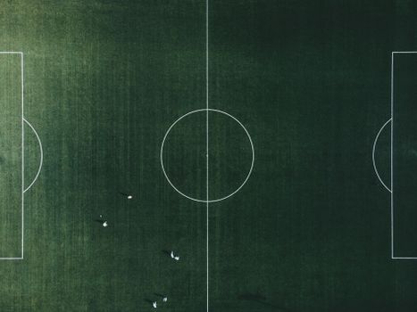 A high-angle shot of a green football field with visible lines and few players.