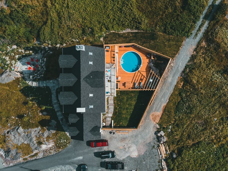 Aerial View Of Secluded Mansion With Pool On Wooden Deck