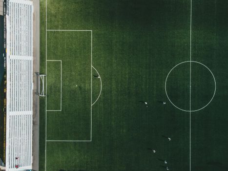 A top-down view of a soccer field with players in action, showcasing the vibrant green grass and sports markings.