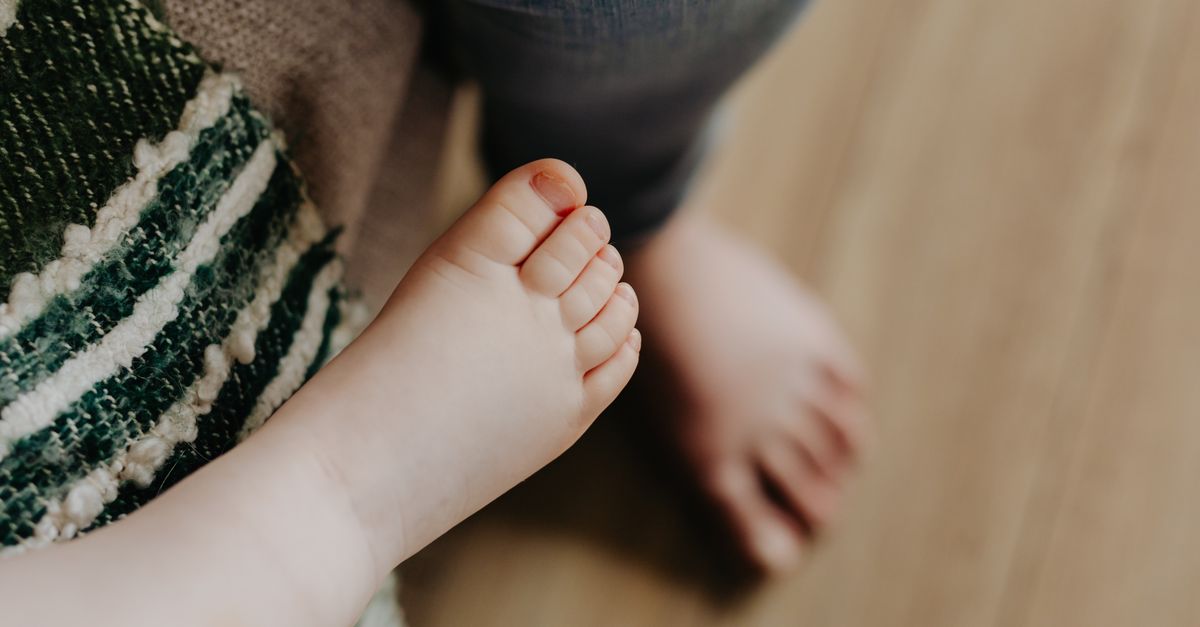 Close-up of baby feet on a wooden floor, depicting a tender childhood moment.