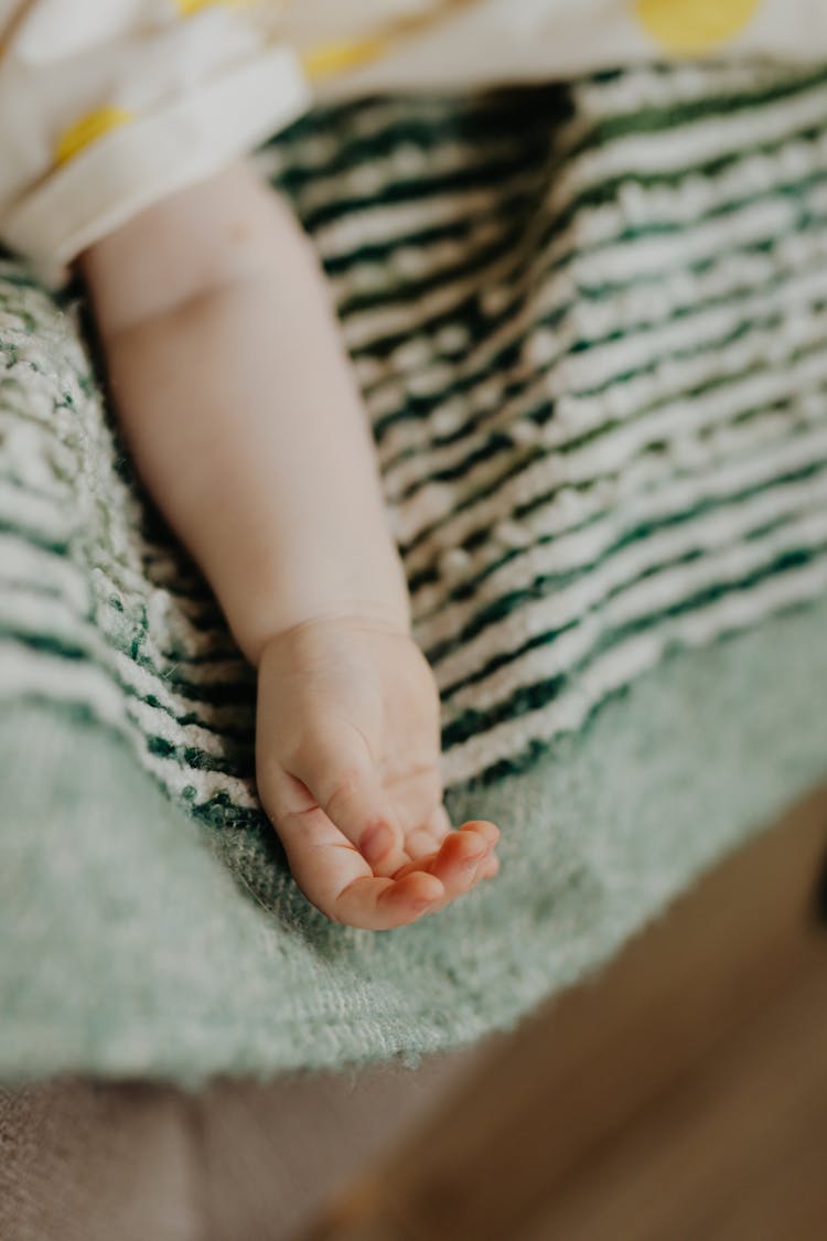 Babys Arm On White And Green Stripped Textile