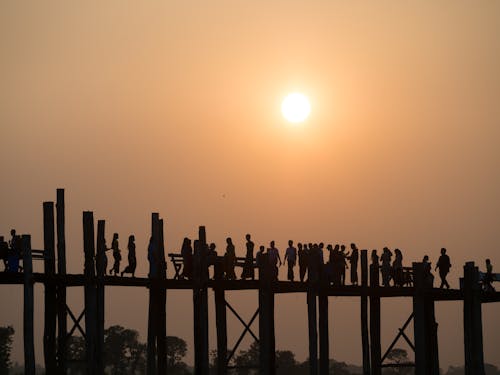 Silhouette of People on a Wooden Bridge During Sunset