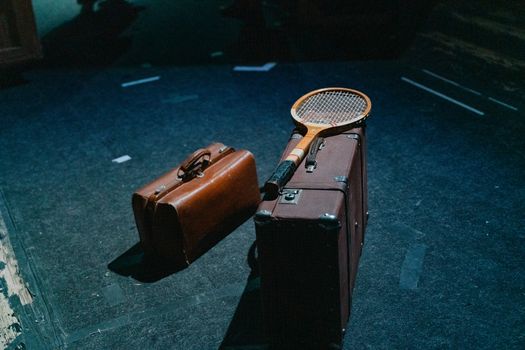 Brown Classic Luggage With Tennis Racket and Overnight Bag on Floor