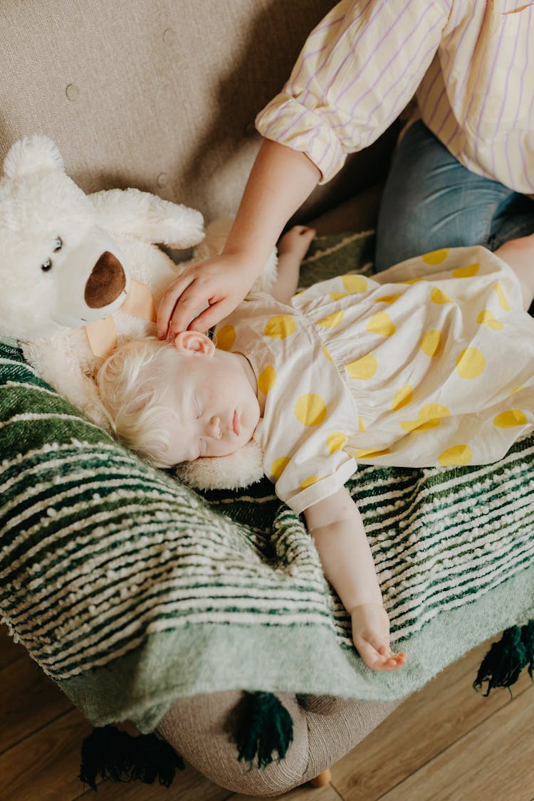 Adult Hand Touching Baby Sleeping On Sofa