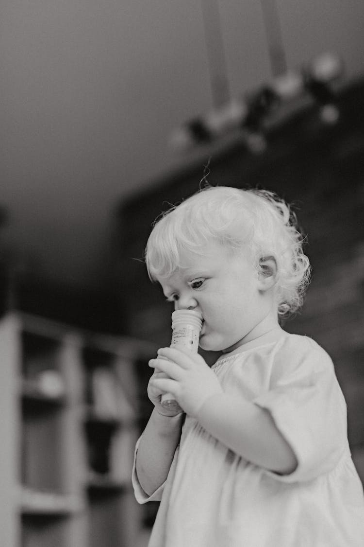 Grayscale Photo Of Toddler Biting An Object