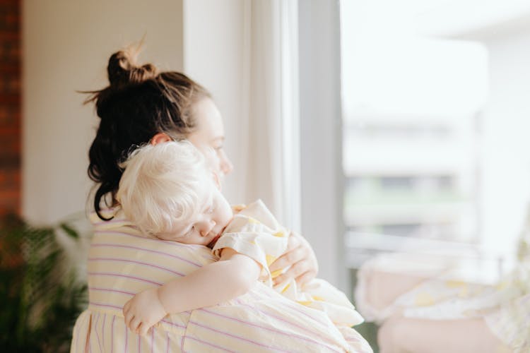 Mother Carrying A Sleeping Child With Her Arms
