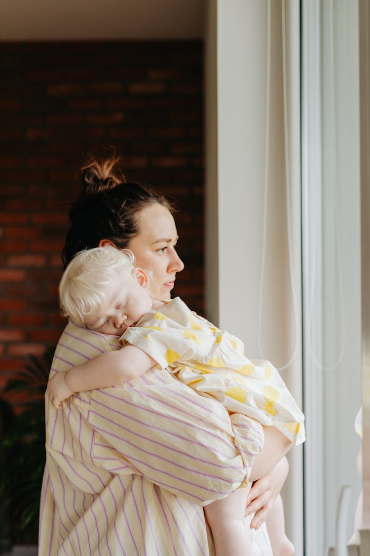 A Woman Carrying Her Sleeping Baby