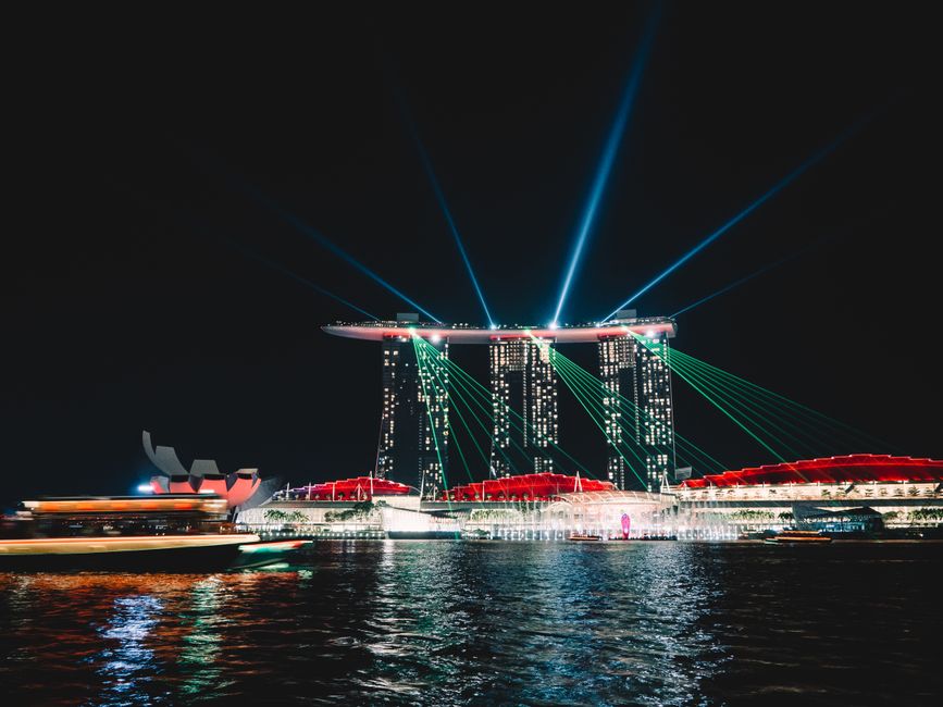 Stunning night view of Marina Bay Sands in Singapore with a vibrant light show reflecting on the waterfront.