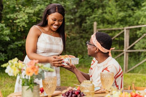 Free A joyful moment of gift exchange between friends at an outdoor summer gathering. Stock Photo