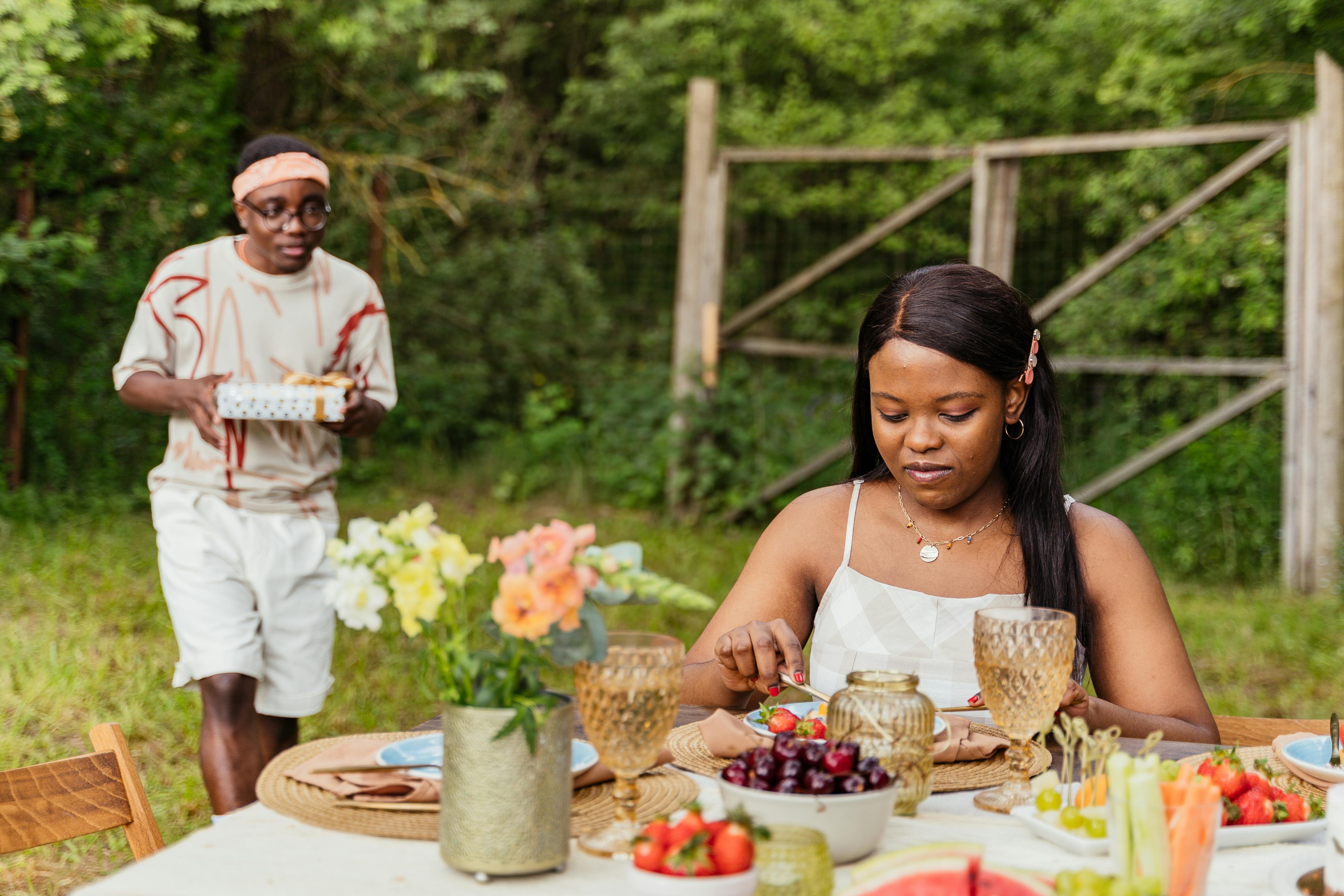 A couple enjoying a picnic surrounded by lush greenery, featuring fresh fruits and warm moments.