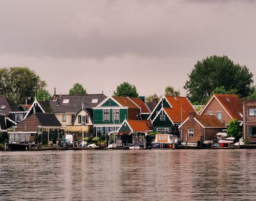 Free Scenic view of traditional Dutch houses along a canal under an overcast sky. Stock Photo