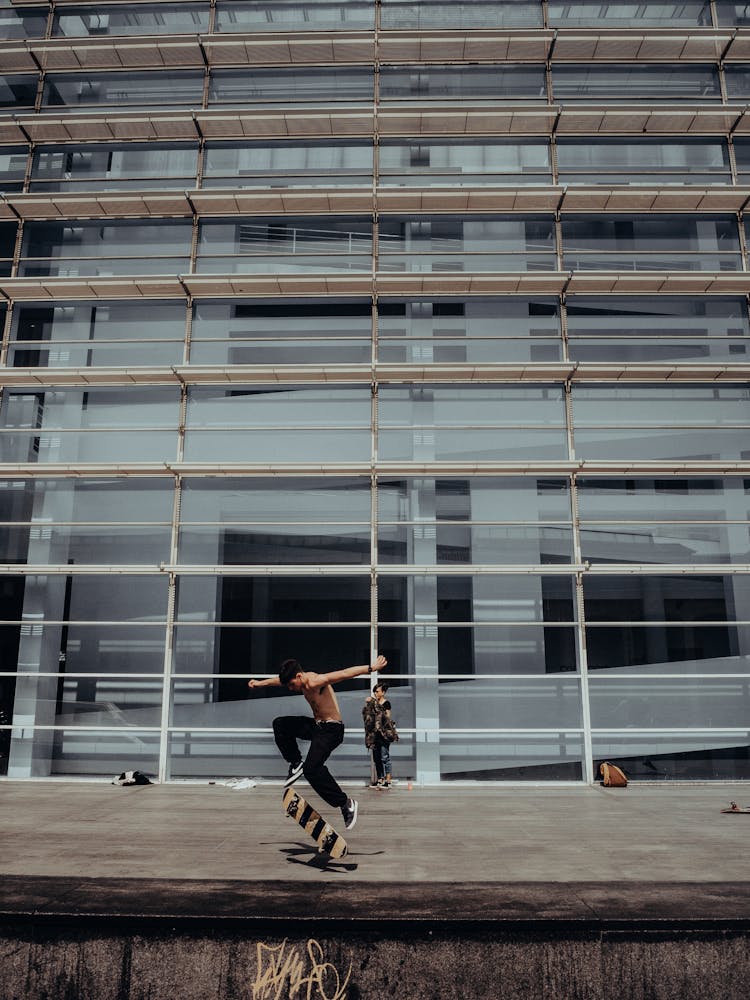 Man Skating On Concrete In Front Of Facade With Scaffolding