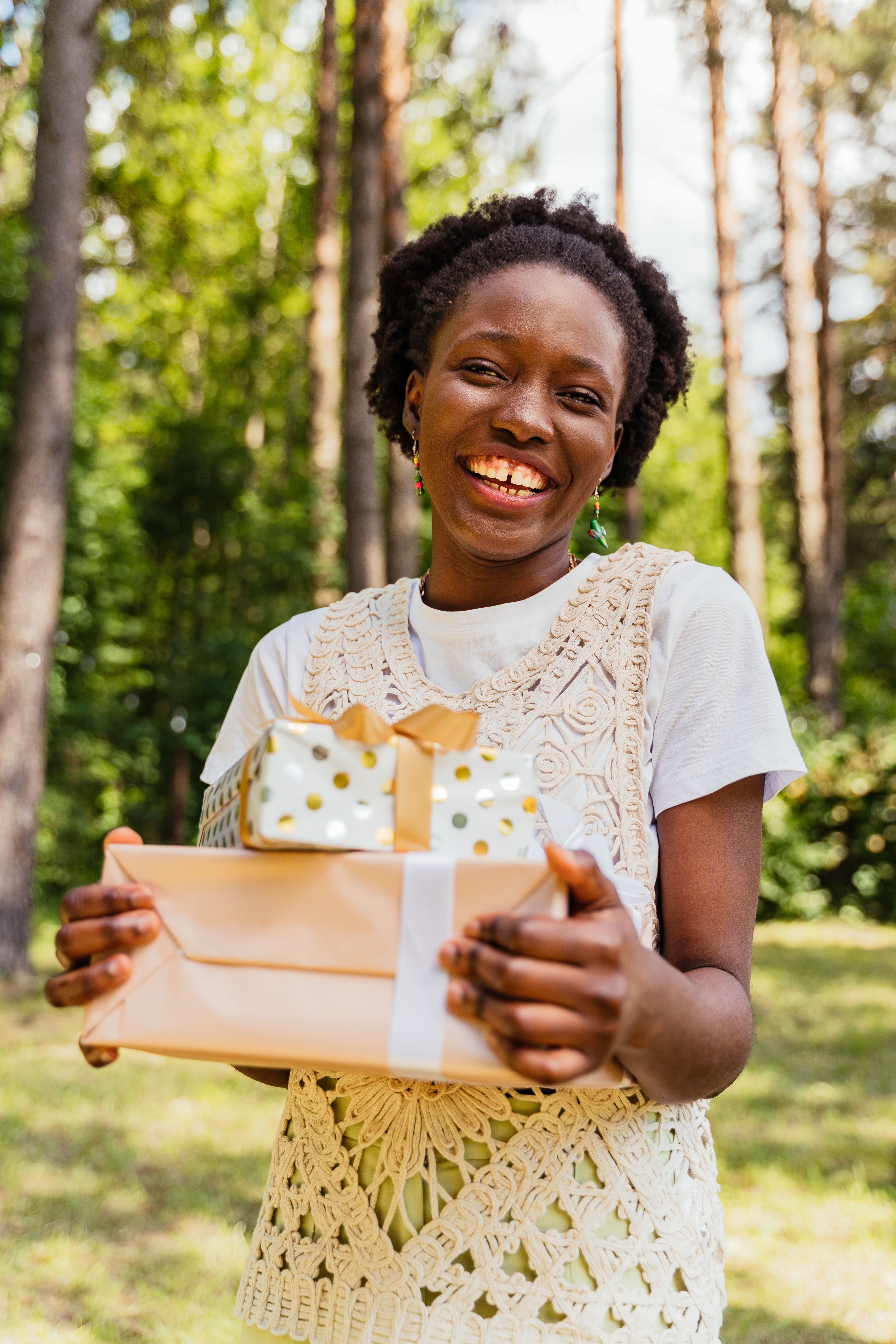 Bien-être & accessoires, Blog - Jeune femme africaine souriante tenant des boîtes cadeaux en extérieur en été