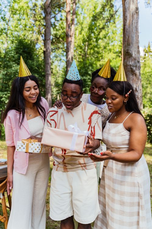 Free Friends enjoying an outdoor birthday party with gifts and party hats. Stock Photo