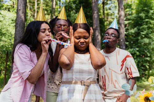 Free Friends enjoying an outdoor birthday party with party hats and noise makers. Stock Photo